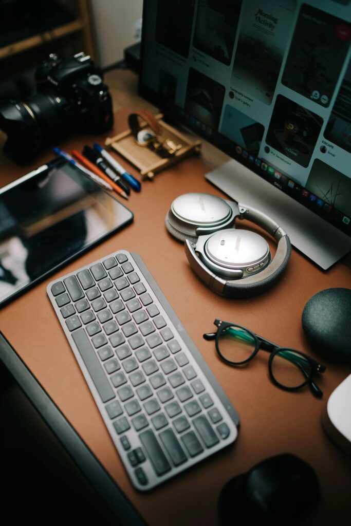 A modern home office desk featuring a digital camera, headphones, and a computer monitor.