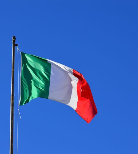 Italian flag flying against a vibrant blue sky, symbolizing national pride and identity.