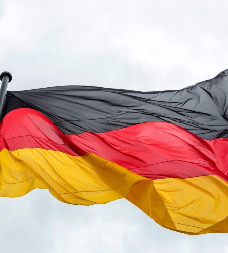 Waving German flag against a cloudy sky, featuring vibrant colors.